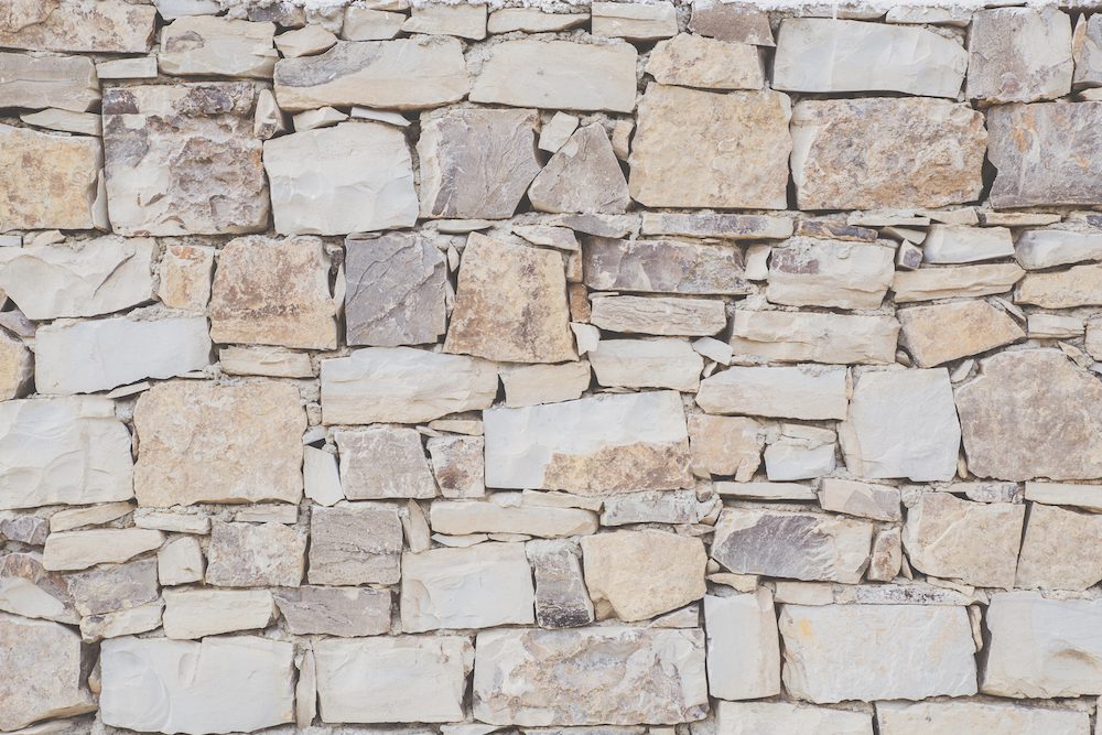 Antique masonry in beige shades. Beautiful textured background from natural stone. Hand laid sandstone or shell rock wall. The concept of reliability, durability, time-tested.