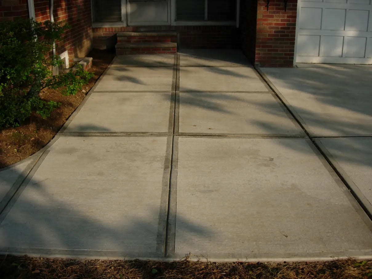 House with a brick wall, windows, doors, stairs, and a white garage door, as well as a concrete driveway