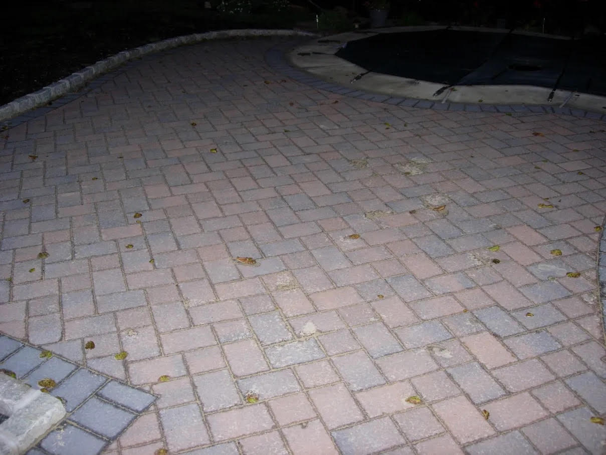 Brick patio with a fire pit in the middle of it, surrounded by a dark background