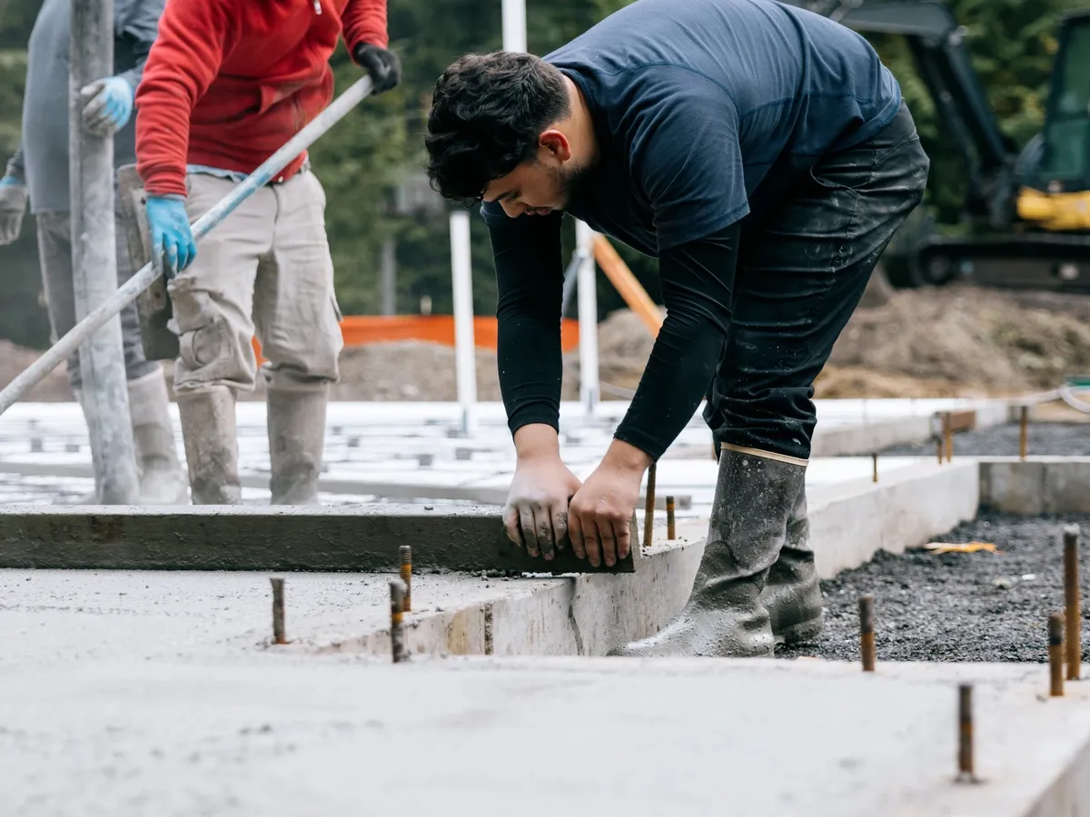 Construction worker pouring concrete into a concrete slab at a construction site
